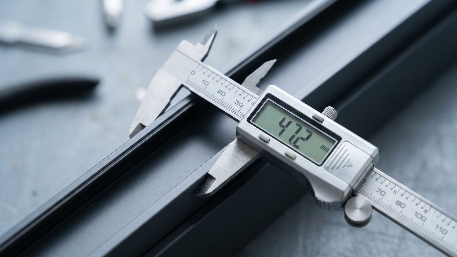 Suwmiarka cyfrowa pokazująca 47,2 mm na antracytowym profilu aluminiowym